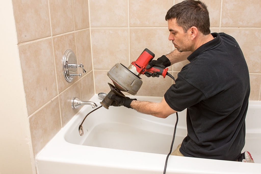 electric drain auger being used by a plumber